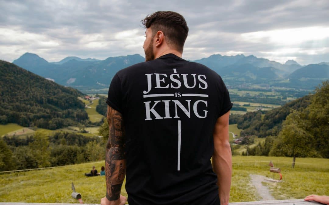 man in black and white crew neck t-shirt standing on green grass field during daytime